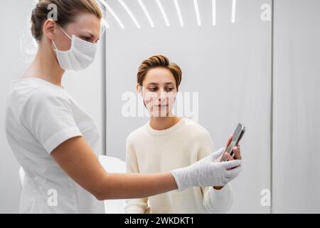 A young woman shows examples of the job she wants to get on her smartphone. Beauty salon. Stock Photo