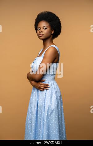 Studio portrait black young woman in blue dress with confident glance arms crossed looking at camera Stock Photo