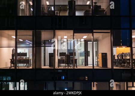 Business building with office and workspaces with desks, laptops and armchairs at night. Work, career and finances Stock Photo