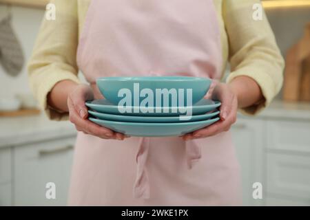 Woman holding plates in kitchen, closeup view Stock Photo