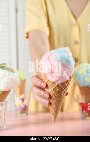 Woman holding waffle cone with cotton candy indoors, closeup Stock Photo