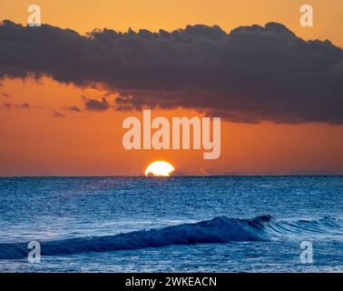 A sunset in Barbados on a sunny day in june with a small wave in the foreground Stock Photo
