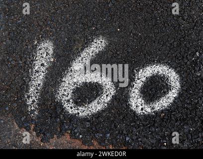 Number 160 painted with spray paint on the asphalt of the street Stock Photo
