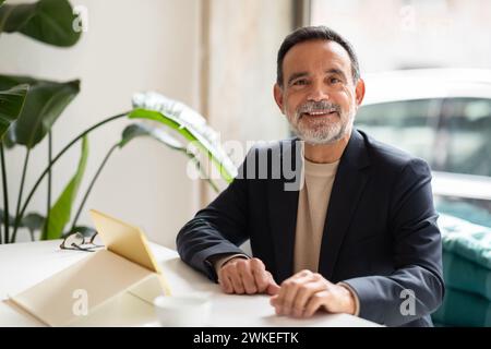 Affable mature man with a beard, wearing a blazer over a sweater, smiling at the camera Stock Photo
