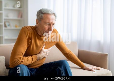 Senior man suffering from heart attack at home Stock Photo