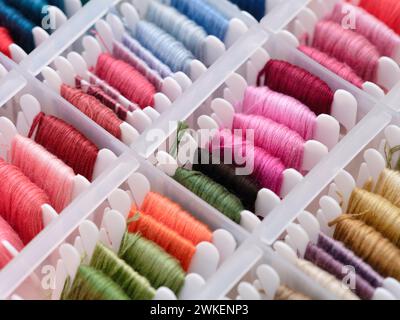 Bobbins with different colour embroidery threads in a plastic sorting box. Stock Photo