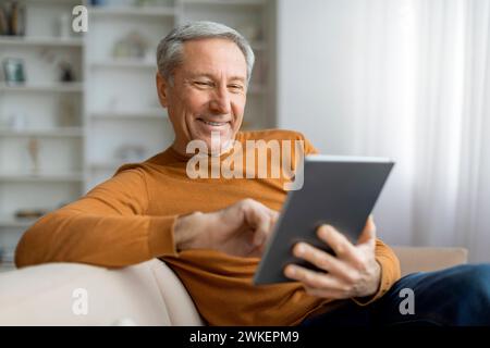 Happy senior man chilling at home, using tablet Stock Photo