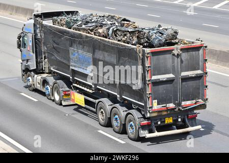 Renault hgv lorry in motion open top tipping semi trailer truck combination aerial side back rear view load of scrap metal on M25 motorway England UK Stock Photo