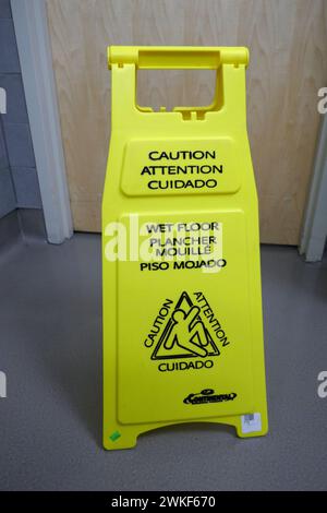 Sign in public bathroom warning of a recently cleaned,  wet floor. Stock Photo