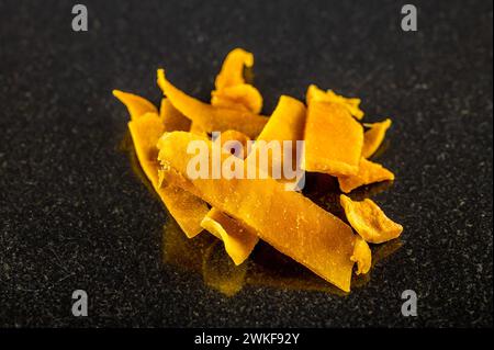 A close up view of dried mango pieces in a pile on a dark marble platter Stock Photo