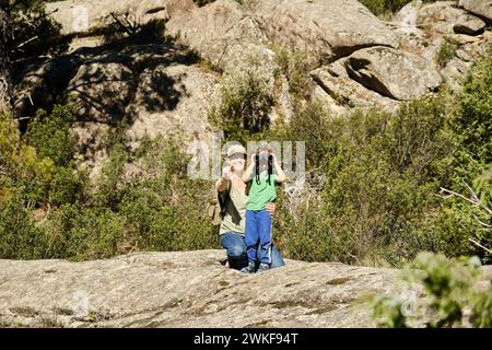 A mother and son observe animals with binoculars in springtime Stock Photo