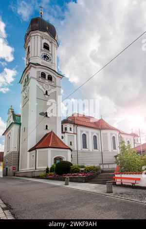 North-side wide angle view of the St. Andreas Church in Nesselwang / Bavaria from in front of a blue sky with large white clouds with lens flares in t Stock Photo