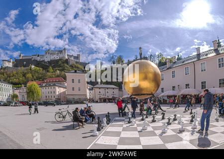 SALZBURG, AUSTRIA - APRIL 27, 2023: Chess game drawn on asphalt in Kapitelplatz, near monument to Paul Fuerst 'Sphere', a golden ball. Stock Photo