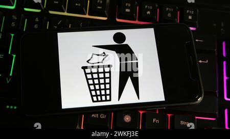 Viersen, Germany - January 9. 2024: Closeup of mobile phone with black and white trash sign symbol on computer keyboard Stock Photo