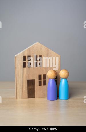 People and house figurines. The owners are standing near the house. Buying and selling real estate. Housing prices. Finding the best home to buy. Affo Stock Photo