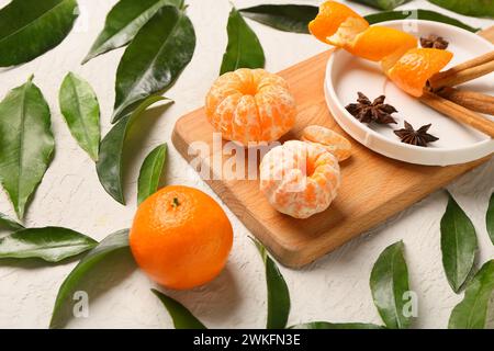 Wooden board of sweet mandarins with cinnamon and star anise on white background Stock Photo