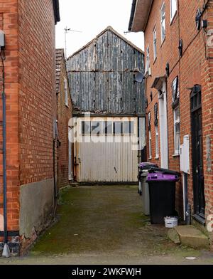 Which came first? the houses or this old garage with a big cream door, down the bottom of a alley in Lincolnshire village of Wainfleet All Saints Stock Photo