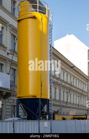 Concrete mixing silo located near a construction site in Europe, . Yellow Mobile cylindrical container facilities.  renovation activities. Stock Photo