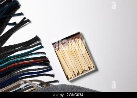 Generic flat lay with matches in a box, scarf and beanie knitted fabric on white background. Winter concept Stock Photo