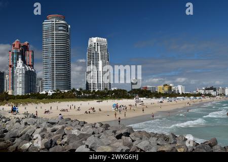 People enjoy a sunny February day at South Pointe beach, Miami Beach, Florida, overlooked by Portofino Tower and North & South Continuum towers. Stock Photo