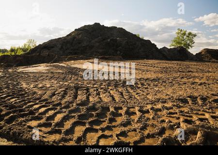 Heavy tire tracks and mound of sand mixed with soil in commercial sandpit. Stock Photo