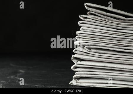 Stack of newspapers on dark stone table, space for text. Journalist's work Stock Photo