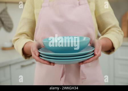Woman holding plates in kitchen, closeup view Stock Photo