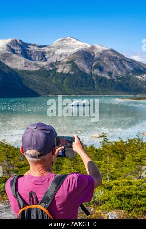 Man photographing the cruise ship Stella Australis in Pia Bay in front of the Pia Glacier, Alberto de Agostini National Park, Avenue of the Glaciers Stock Photo