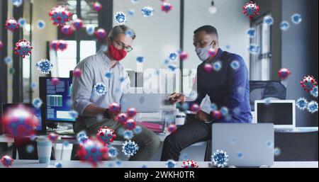 Image of virus cells floating over diverse businessmen with face masks at meeting Stock Photo