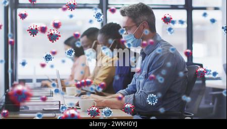 Image of virus cells floating over diverse business people with face masks in office Stock Photo