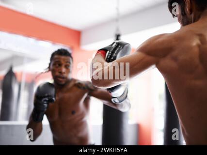 Man, boxing and personal trainer for workout practice in combat gym for competition endurance, performance or progress. Male person, coach and pad Stock Photo