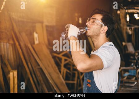 Worker drinking water in an wood industrial factory. Working hydrated watering at work. Water to the body healthcare. Stock Photo