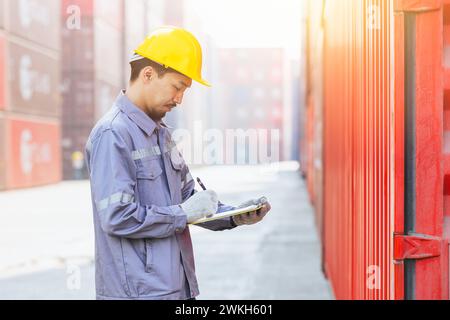 Asian male customs worker smart working check loading cargo container in port shipyard. Japan shipping logistics industry staff man on duty. Stock Photo