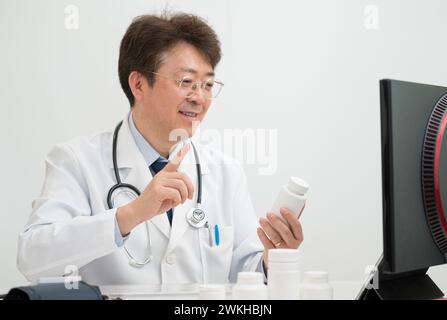 A middle-aged male doctor performing telemedicine using a computer Stock Photo