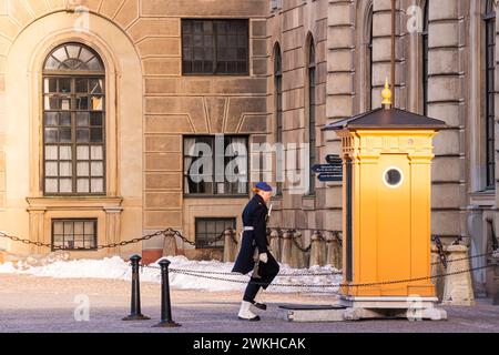 Swedish female Royal Guard in navy blue winter uniform protecting the Royal Palace in Stockholm. Guard walking to the guard booth Stock Photo