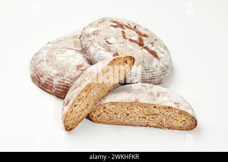 Three artisan wheat bread loaves with one cut in half, isolated on white background, showcasing crust and airy texture. Traditional bakery products co Stock Photo