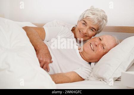 Senior couple, portrait and relaxing in bed, smiling and love in retirement for bonding on weekend. Elderly people, bedroom and resting or happy in Stock Photo