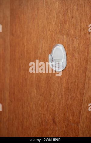 White plastic stick on hanger hook on a wooden door, close up shot, no people. Stock Photo