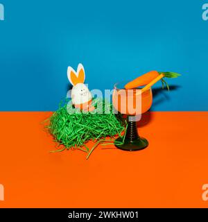 Easter egg and carrot in a glass on a colored background. Easter creative concept. Stock Photo