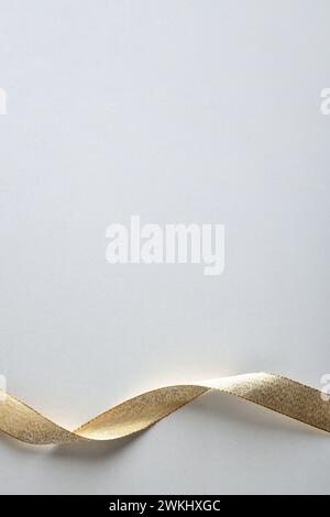 Shiny gold ribbon with ripples at the bottom on isolated white background. Top view. Stock Photo
