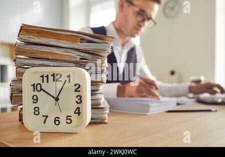 Table Clock and Stack of Papers on Desk Stock Photo