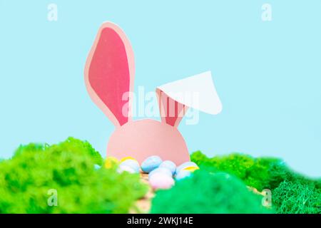 The pink rabbit is hiding in the grass. Easter greeting card with Easter symbols. Stock Photo