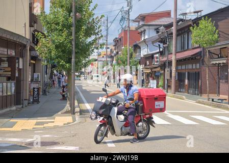 Japanese postman on a motorcycle in the streets of Takayama on a sunny summer day. Japan, Takayama, 08 29 2019. Stock Photo