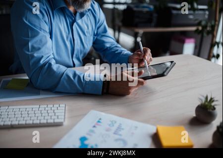Man is sitting at a desk using a tablet computer Stock Photo