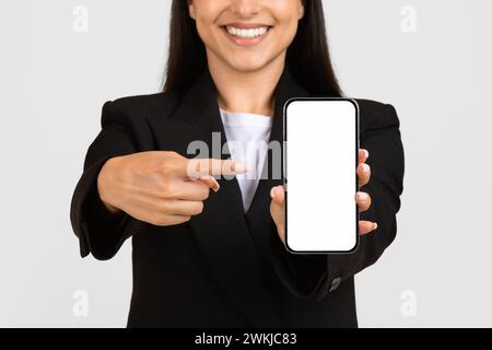 Happy woman in business attire presenting smartphone screen Stock Photo