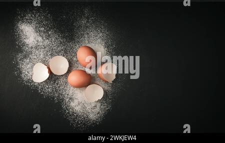 Flour and eggs: Ingredients for cooking many dishes. Kitchen background. Bakery products. Chicken egg broken among other eggs. Brown eggs and egg yolk Stock Photo