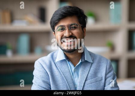 Portrait of happy young Indian entrepreneur man in office Stock Photo