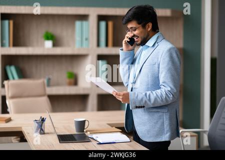 Indian Businessman Discussing Documents Over the Phone In Office Stock Photo