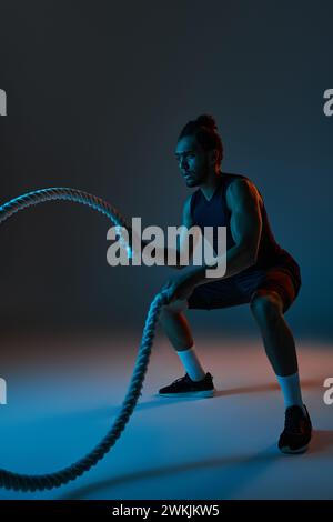 attractive young african american man in black sport uniform training actively with battle ropes Stock Photo