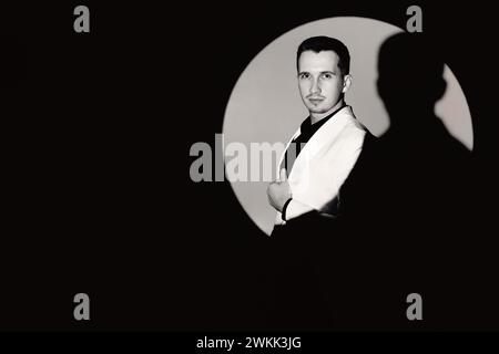 elegant man in white suit tuxedo in the circle of light, copy space. black and white Stock Photo